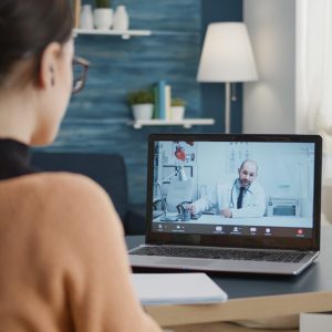 Young patient atttending telemedicine appointment call with doctor, discussing about healthcare and treatment. Sick woman doing remote video call consultation with medic for online telehealth.